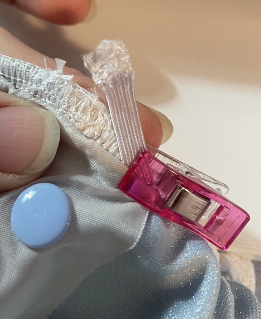 Pink sewing clip holding new elastic against cloth diaper.