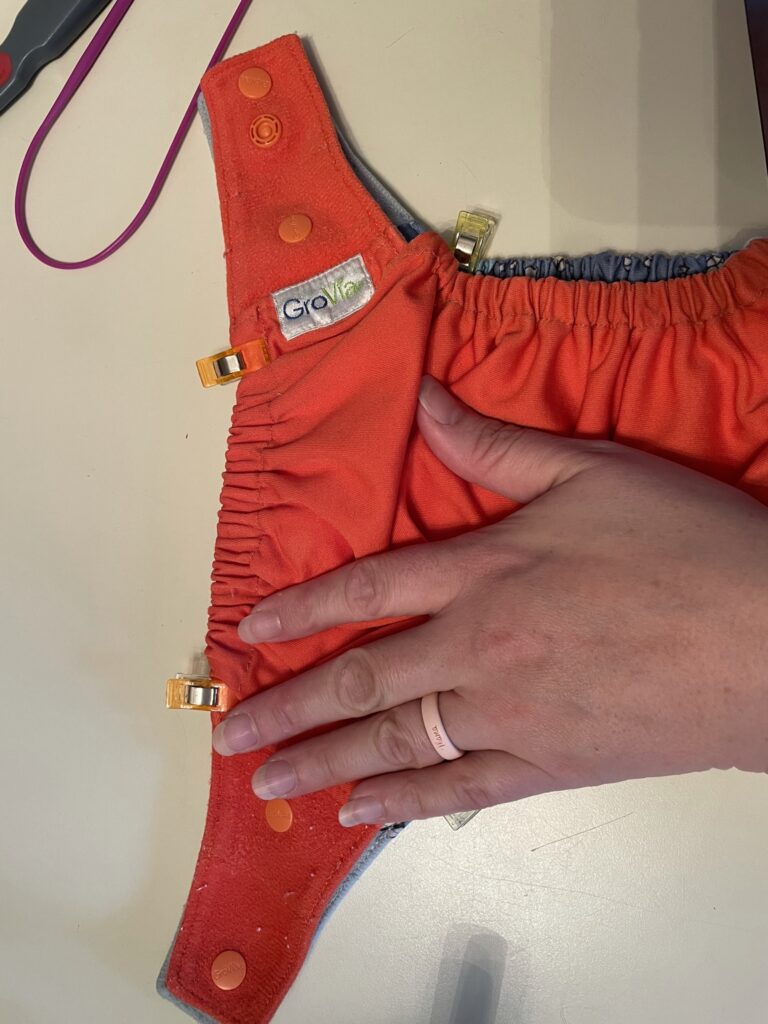 Dark orange Grovia cloth diaper with sewing clips.